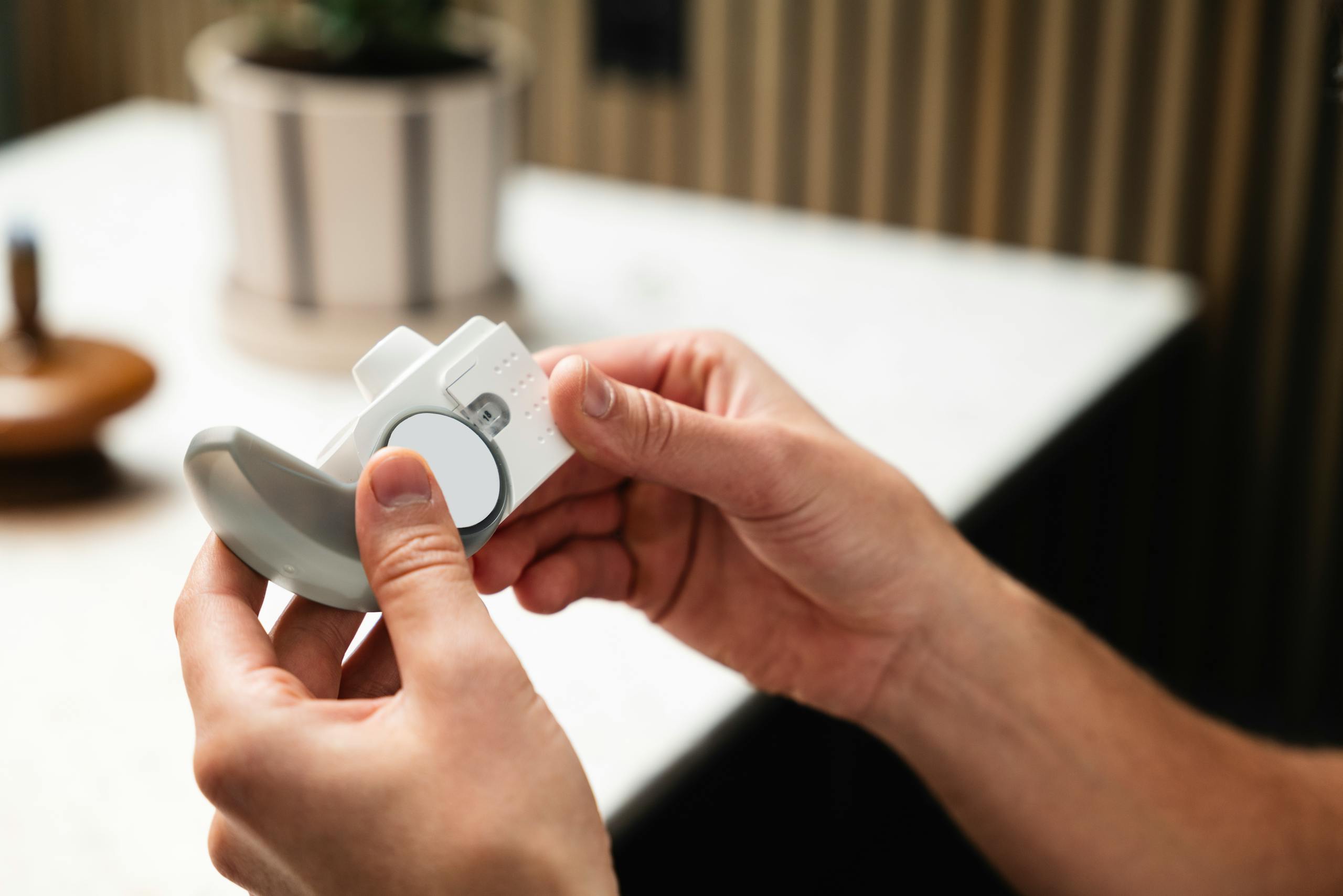 Close-up of hands holding an asthma inhaler, indoors in a modern setting.