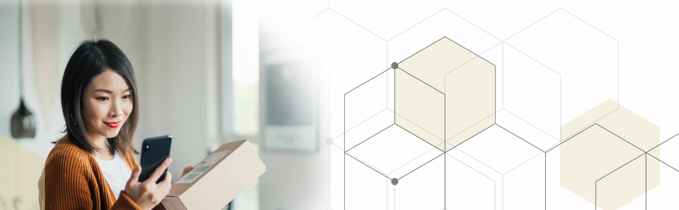 woman holding box and looking at cell phone