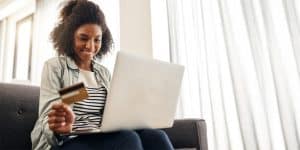 woman holding a credit card and looking at a computer